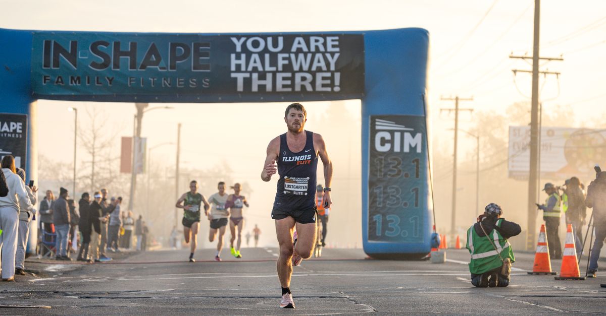Runner approaching the halfway mark in a marathon event with spectators and photographers capturing the moment.